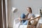 Young millennial redhead woman sitting on modern chair enjoying morning at home