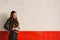 Young millennial woman standing in profile on white and red wall background spoiled with copy space for text, real people looking