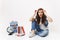 Young mistrustful puzzled woman student in denim clothes removing glasses sitting near globe, backpack, school books