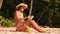 Young Mixed Race Attractive Girl in Bikini Sunbathing on Tropical Paradise Sandy Beach and Using Mobile Tablet Gadget