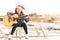 Young mixed race girl playing guitar, singing and smiling joyfully by swimming pool, with christmas santa hat
