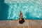 Young mixed-race woman with sunglasses leaning on edge of pool