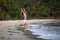 Young mixed-race woman walks along a polluted tropical beach.