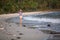 Young mixed-race woman walks along a polluted tropical beach.