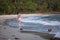 Young mixed-race woman walks along a polluted tropical beach.