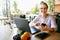 Young mixed race woman working with laptop in cafe looking at camera. Asian caucasian female studying using internet