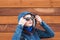 Young Model PosGirl in a blue jacket with a hood, sunglasses, wooden background, looking to side,