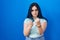 Young modern girl with blue hair standing over blue background ready to fight with fist defense gesture, angry and upset face,