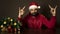 Young modern santa claus is sitting at a table near the tree. Emotional portrait. Rock