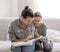 Young mom and daughter have fun together, doing homework with a book and a phone