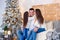 Young mom, father, and their little daughter lovely sitting near Christmas tree on sofa.