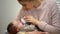 Young mom feeding little baby son from bottle, infant formula artificial feeding