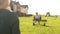 Young mom gets off swing to push toddler son on swing at playground park. Mother and son on a sunny day, happy childhood