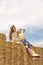 Young mom and little daughter have fun on the farm playing on the haystack. Countryside summer weekends