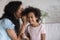 Young mom whispering in ear share secret to smiling daughter