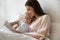 Young mommy lying in bed with daughter, reading book.