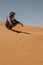 Young moroccan berber man sitting on a Sahara desert dune.