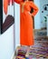 A young Moroccan woman wearing an orange djellaba with high heels.