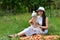 A young mother of 28 years old sits with her son in her arms on a pile of carrots in nature near a forest in a clearing and holds