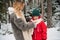 A young mother adjusts her son`s scarf on a frosty morning in the woods