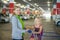 Young mother and adorable daughter in shopping cart on underground car park of supermarket