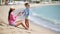 Young mother applying sun cream to kid hand outdoors on tropical beach