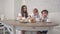 Young mother attending to her little boys having tea at home