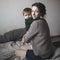 Young mother and baby in knit sweaters playing on bed, concept