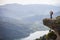 Young mother with baby in sling standing on cliff