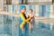 Young mother and baby son are in pool teaches swim