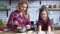 Young mother with blond long hair mixing in plate and small cute naughty girl play with flour on the kitchen table