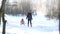 A young mother carries her daughter on a sled