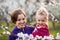 Young mother and child daughter together, hugging and laughing in a Flowering apricot garden. Family outdoors lifestyle