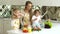 Young Mother With Children Cooking Healthy Food At Kitchen