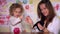 Young mother and cute daughter putting coins into piggy bank.