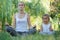 Young mother and cute little daughter meditating in lotus pose together