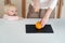 Young mother cuts an orange for the baby who is standing nearby. Safety in the kitchen