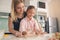 Young mother and daughter cooking dough together