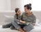 Young mother and daughter have fun together, reading a book at home on the couch