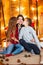 Young mother with a daughter with long hair and an elder son cuddle in the autumn scenery in the studio with pumpkins, plaids and