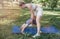 a young mother and daughter perform yoga exercises in the park on a gym mat