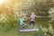 a young mother and daughter perform yoga exercises in the park on a gym mat. healthy lifestyle.