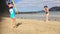 Young mother and daughter play bat and ball on the beach during summer vacation