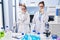 Young mother and daughter at scientist laboratory looking stressed and nervous with hands on mouth biting nails