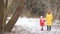 Young mother and daughter on a walk in winter park. They are dressed in bright down jackets