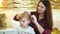 Young mother does hair style for her toddler daughter at festive decorated home