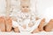 Young mother and father sit with little baby on bed with bare heels on white background. Cute relationship between