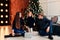 Young mother and father and their little daughter in a New Year decor with gifts and a Christmas tree