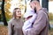 Young mother and father are walking with a newborn baby in the autumn park. Parents look at the child with tenderness