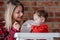 Young mother feeding a child with porridge.